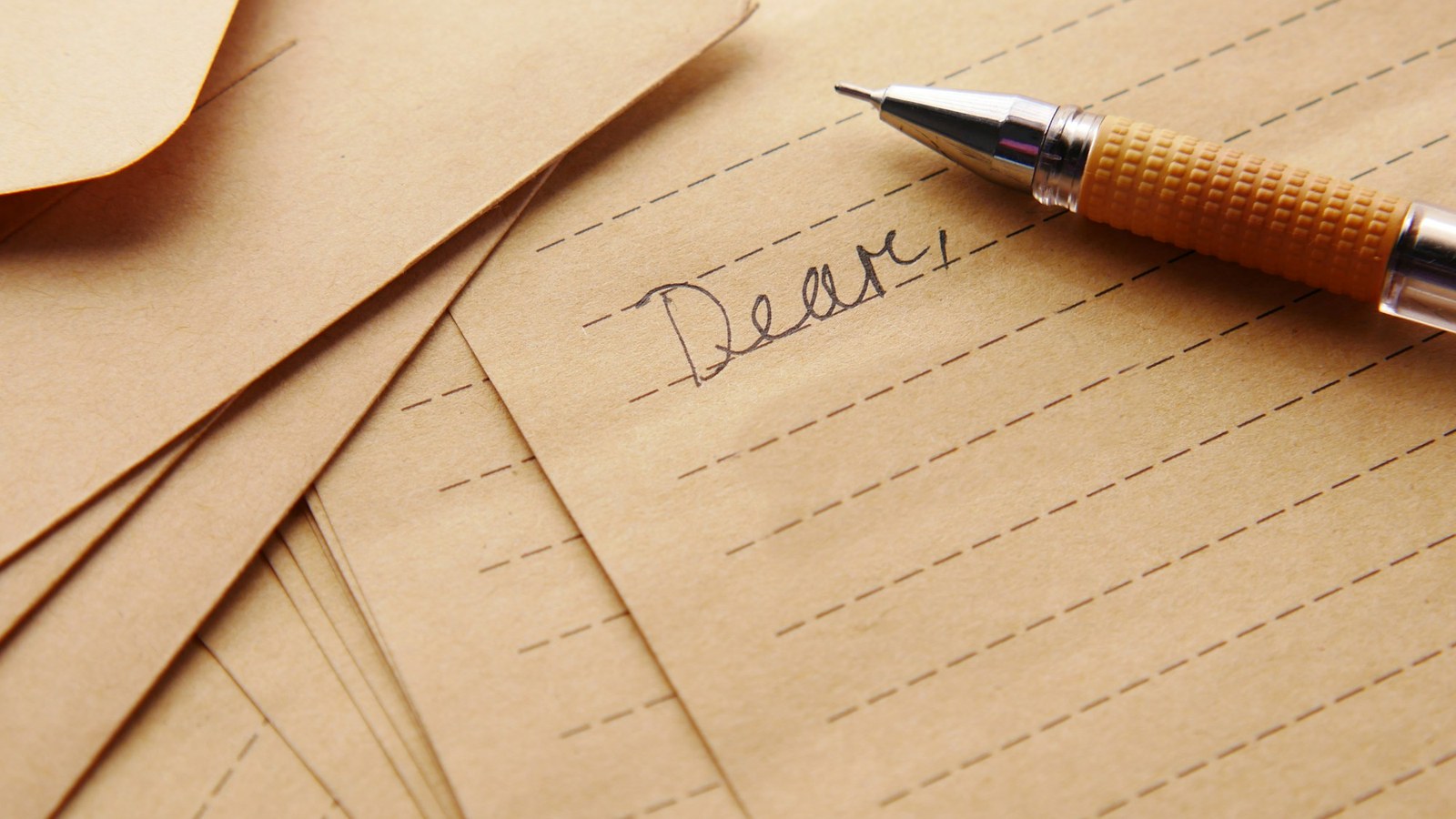封筒と便箋が重なり、ペンで「Dear」と書き出した手紙(作文や手紙を書く一般的な場面)