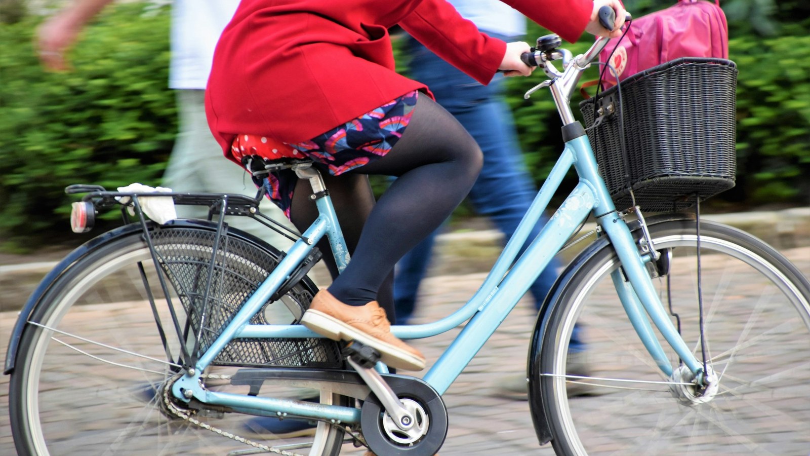 前かご付きの自転車で街を走る人(ママチャリのような、ふつうの自転車の一般的なイメージ)